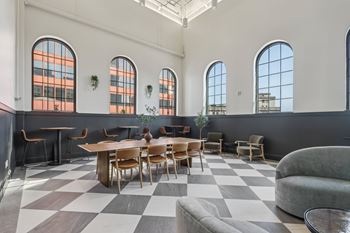 A large room with a checkered floor and a long table with chairs. at LiveWell Apartments, Pittsburgh, PA